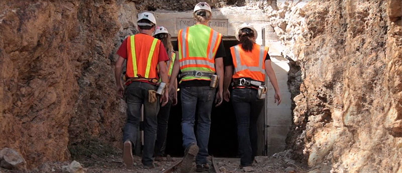 Group of people wearing mining gear entering a mine at surface portal