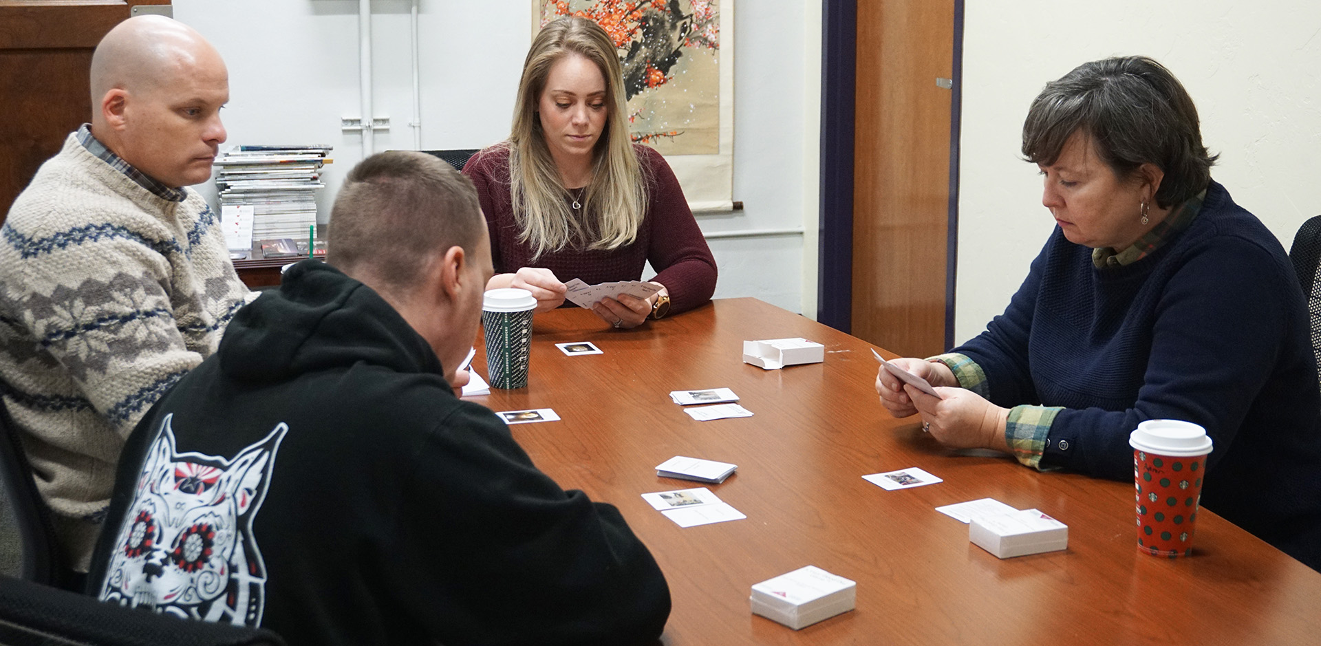 A group of learners sit around a table playing the Very Good Day card game