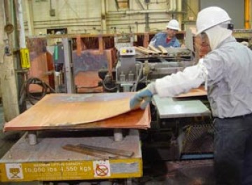 Person feeding copper sheets into press